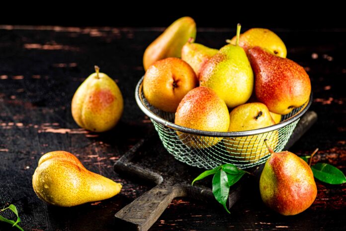 Fresh pears in a basket on dark table.