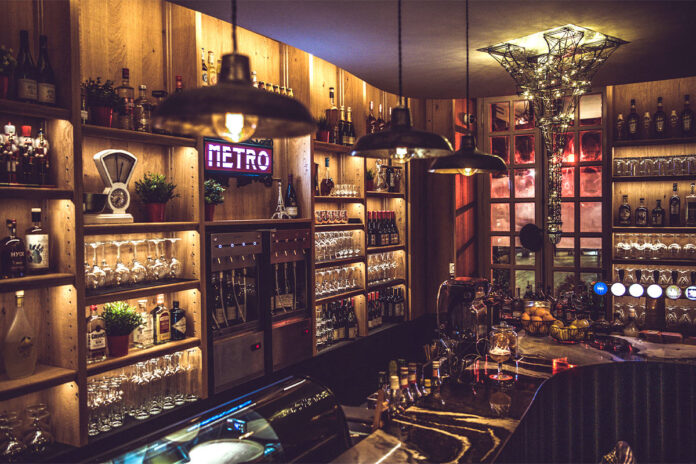Cozy wooden bar interior with wine display.