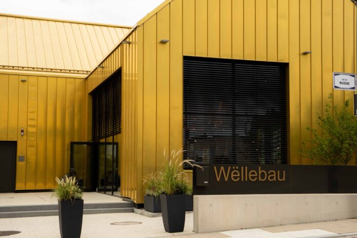 Wëllebau-7 Golden building with modern facade, Wëllebau sign.