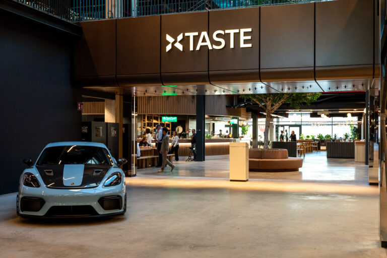 Car in modern restaurant lobby with TASTE sign.