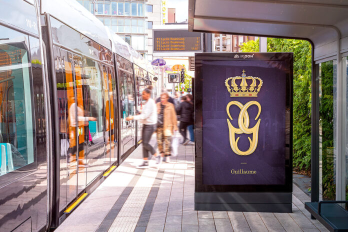 Modern tram at city stop with digital display ad.