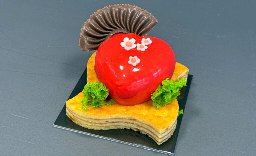 Heart-shaped dessert with chocolate and floral decorations.
