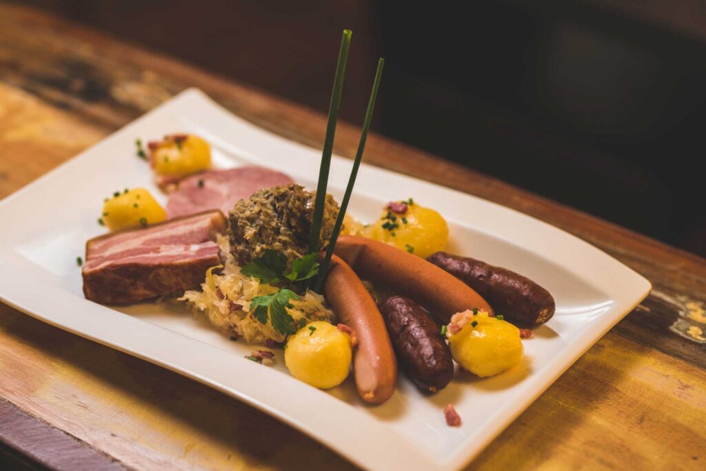Assorted meats and potatoes on a white plate.