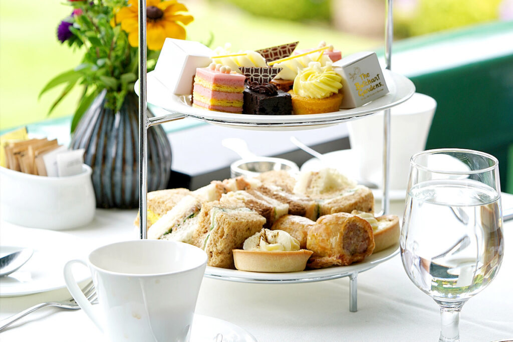 Afternoon tea with sandwiches and desserts on tiered tray.
