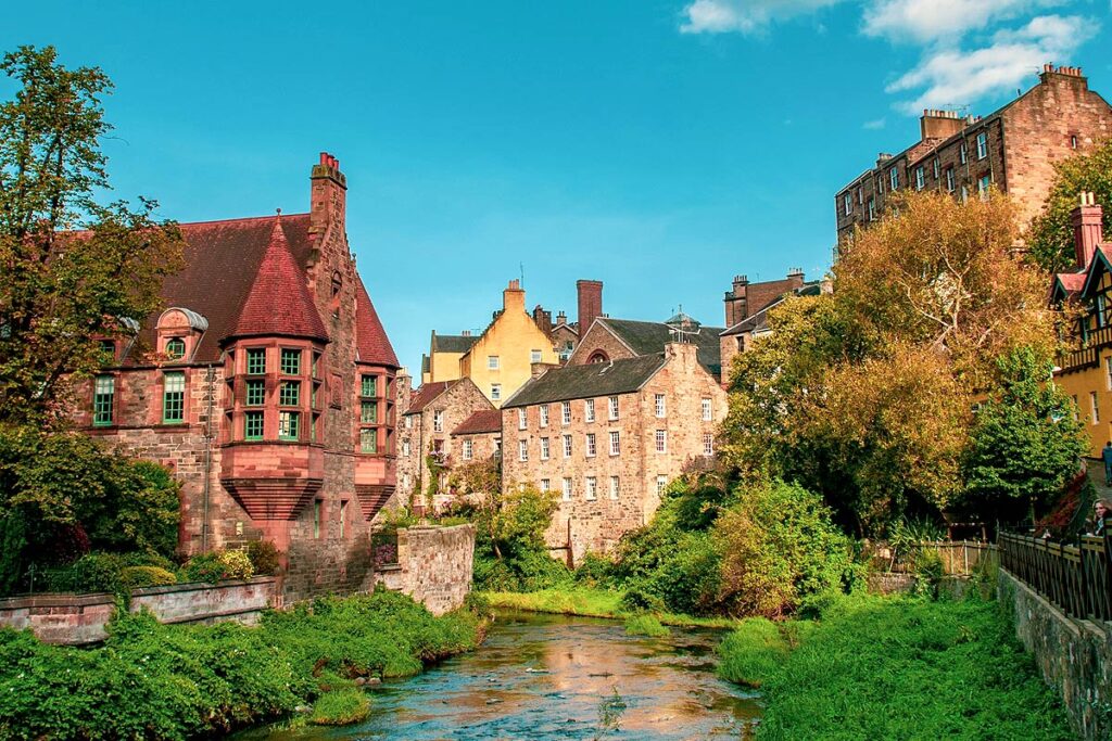 Historic stone buildings by a lush riverbank.