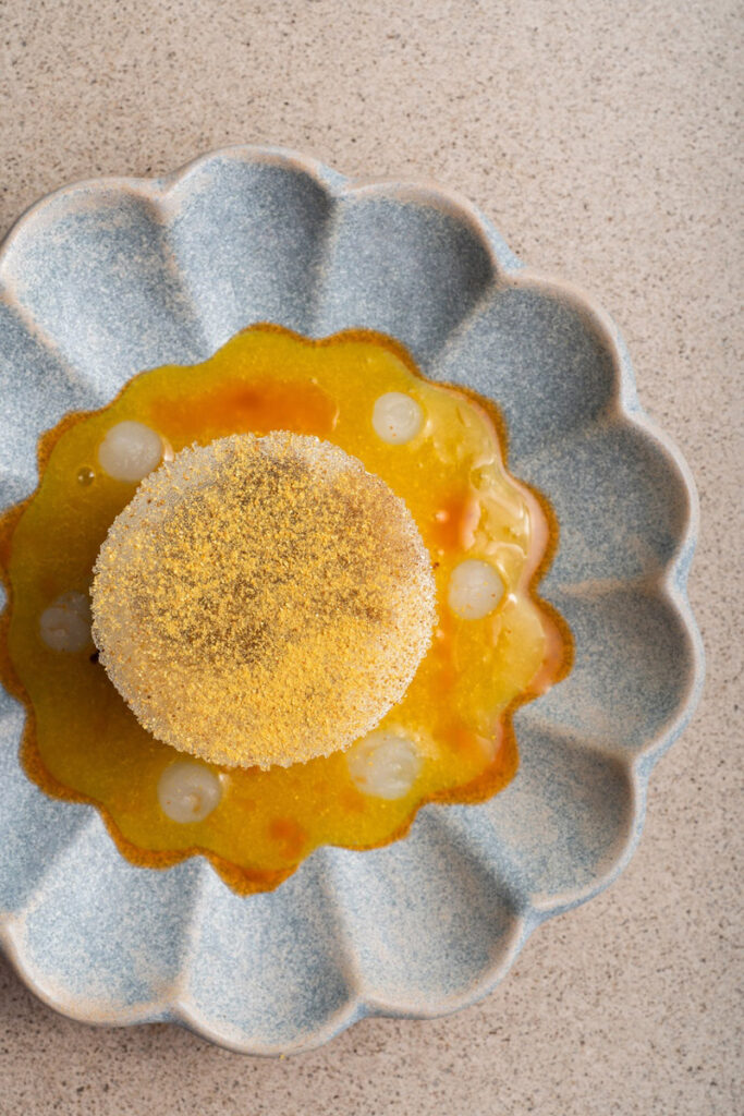 Gourmet dish on scalloped ceramic plate with sauce.