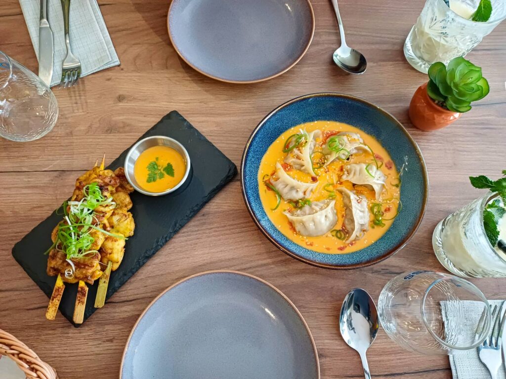Assiette de dumplings et brochettes avec sauces.