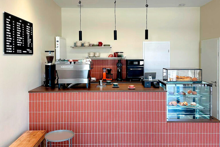 Modern cafe counter with coffee machine and pastries.