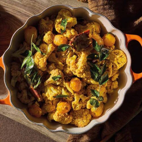 Curried cauliflower in orange casserole dish.