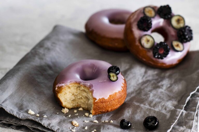 Purple glazed donuts with blackberries and blueberries.