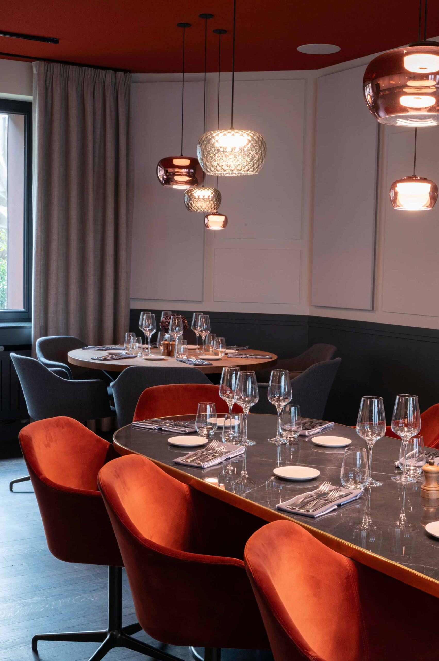 Elegant restaurant interior with modern lighting, set tables.