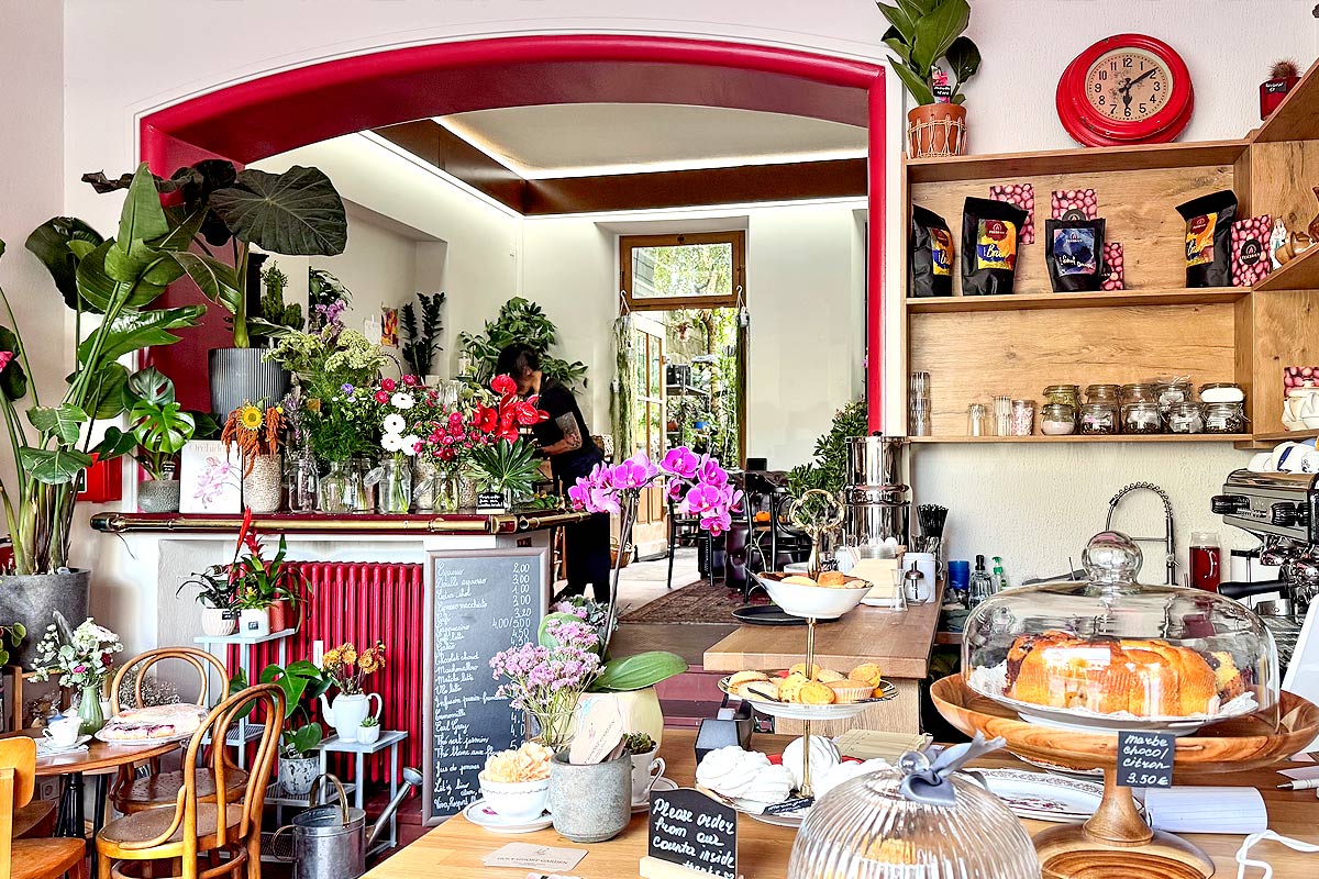 Cozy cafe with flowers, pastries, and espresso machine.