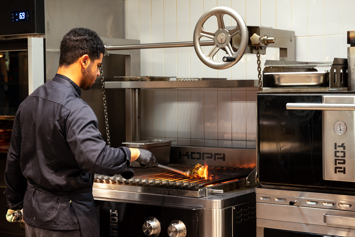 Chef grilling meat in restaurant kitchen.