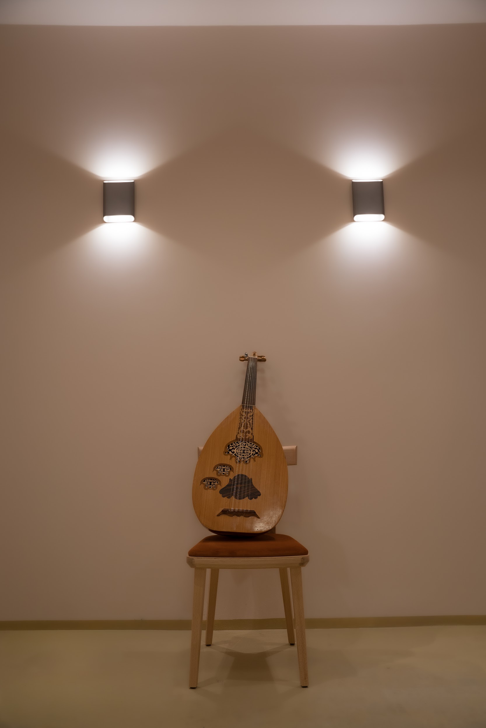 Wooden oud instrument on chair with glowing wall lights.