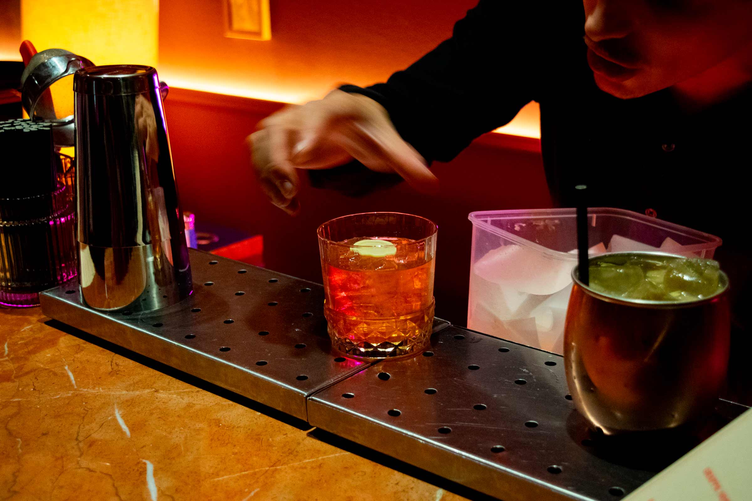 Bartender preparing drinks at a bar counter.