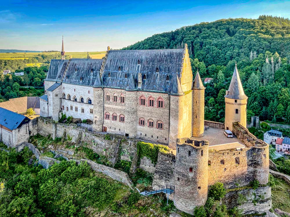 Medieval castle on hilltop surrounded by forest.