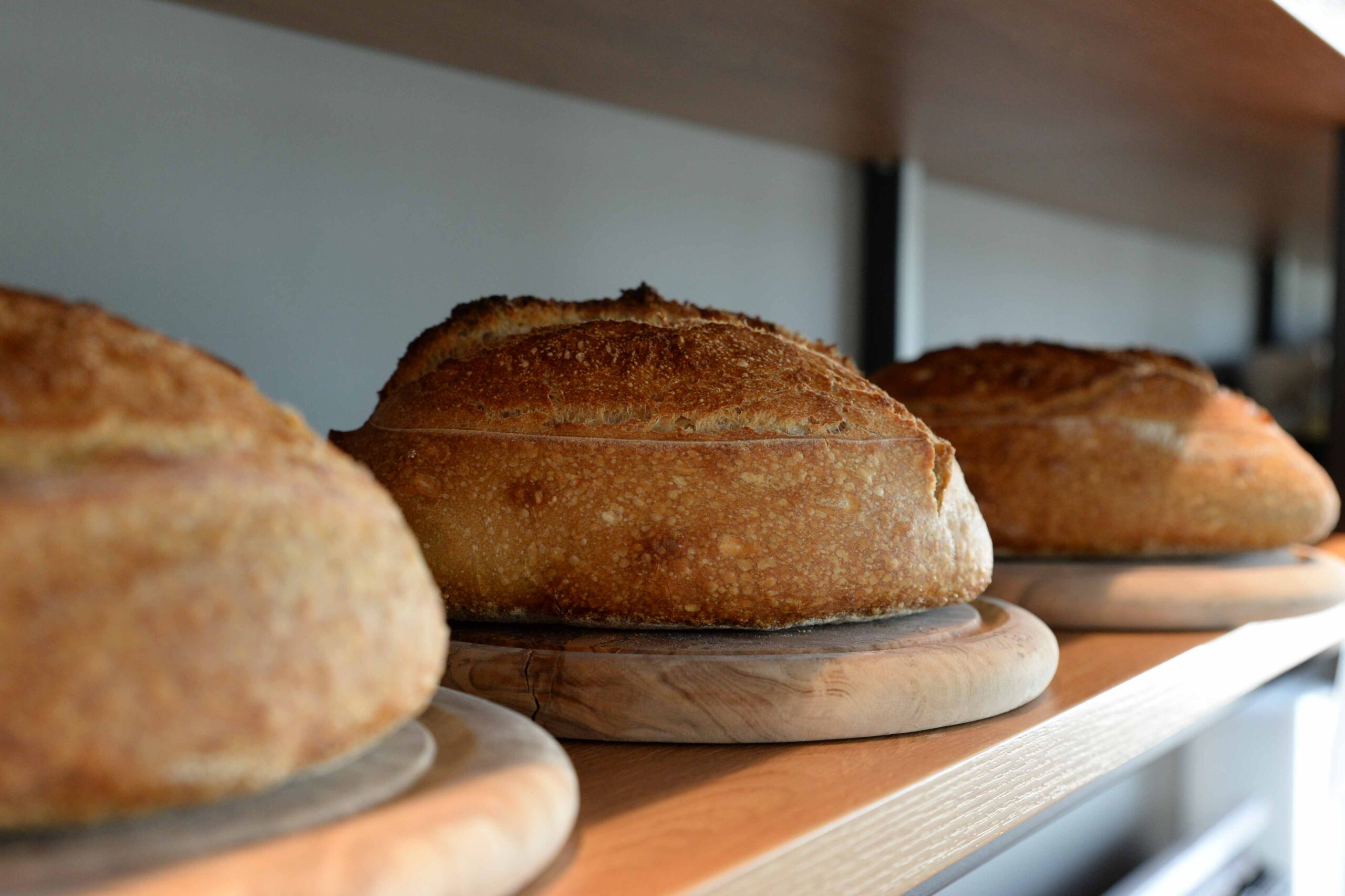 Three round loaves of bread on wooden trays.