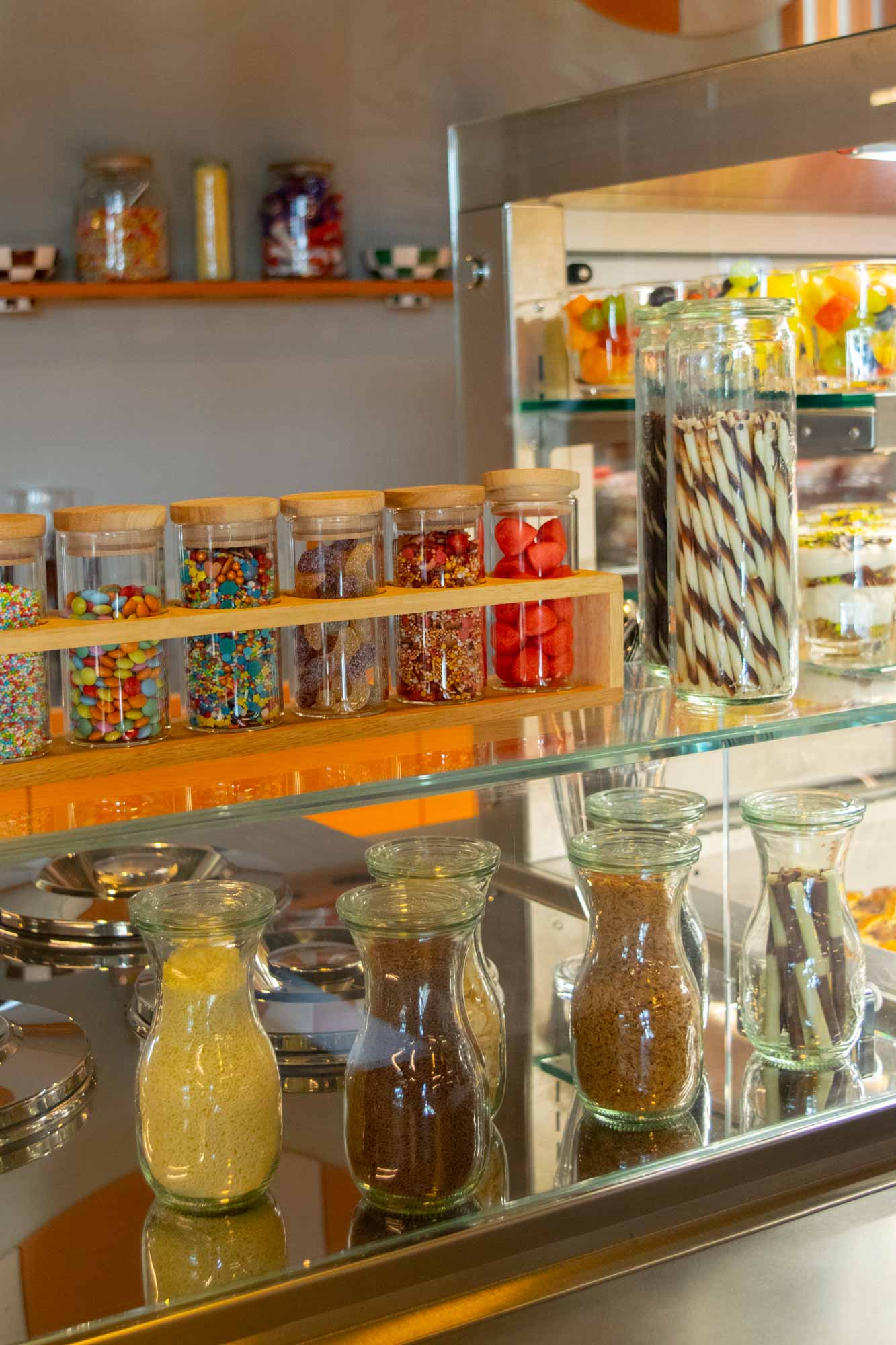 Candy jars on a glass shelf.