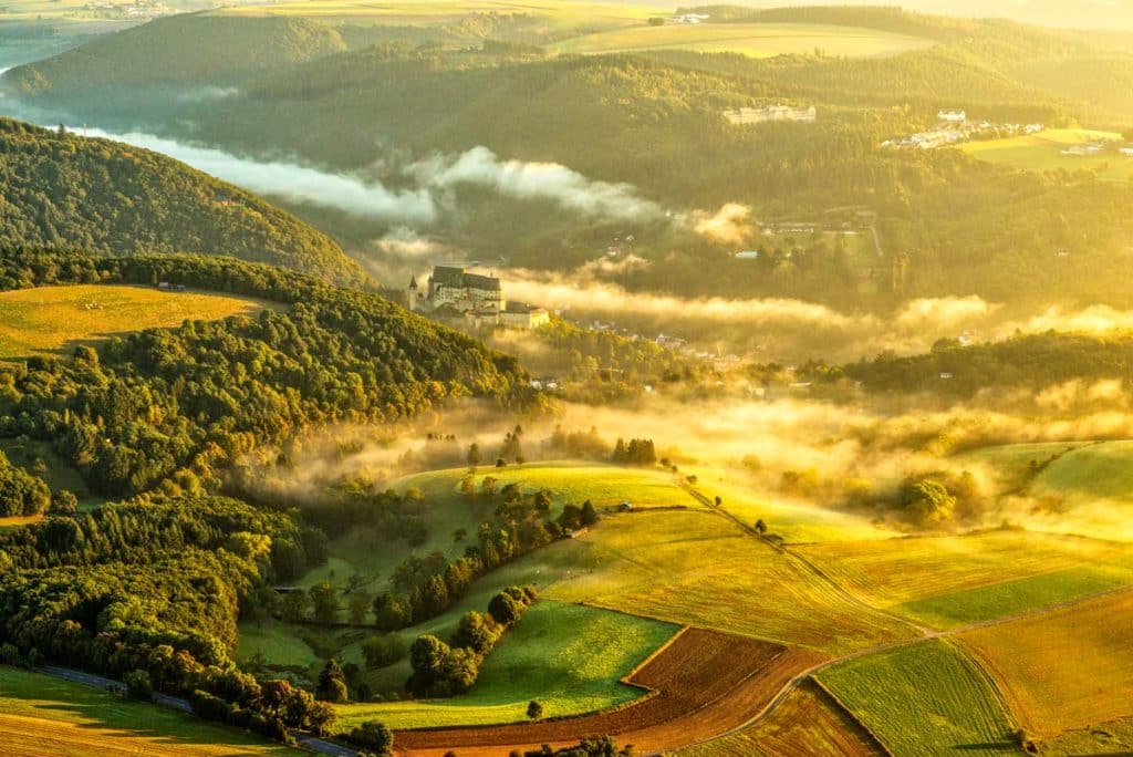 Aerial view of misty green hills and fields.