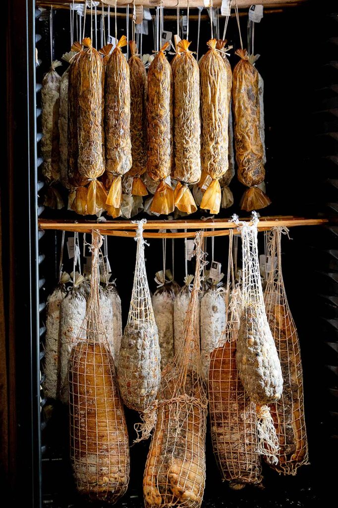 Cured meats hanging in a refrigerator.