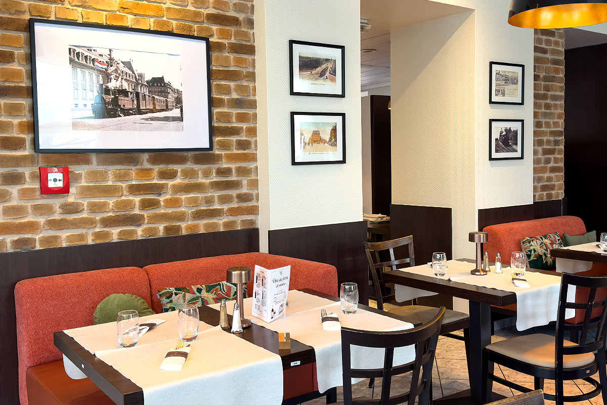 Cozy restaurant with tables and framed pictures on walls.