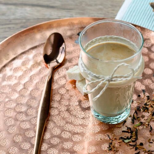 Licorice tea in a glass on copper tray.