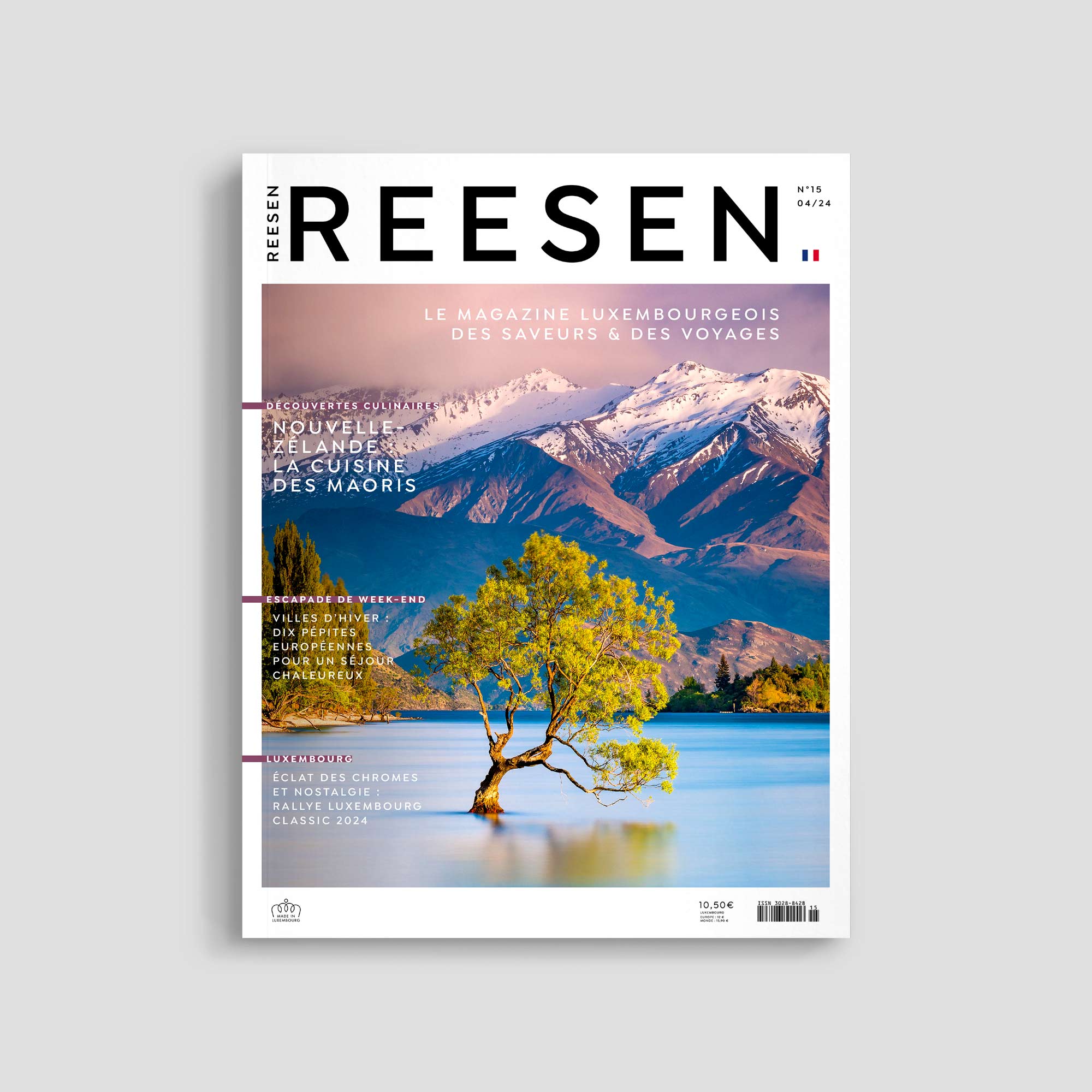 Magazine cover with snowy mountains and tree in lake.